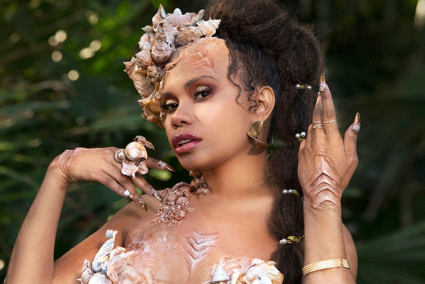 The singer Ngaiire as a mermaid - shells sprouting from her body, gills on hands and chest.