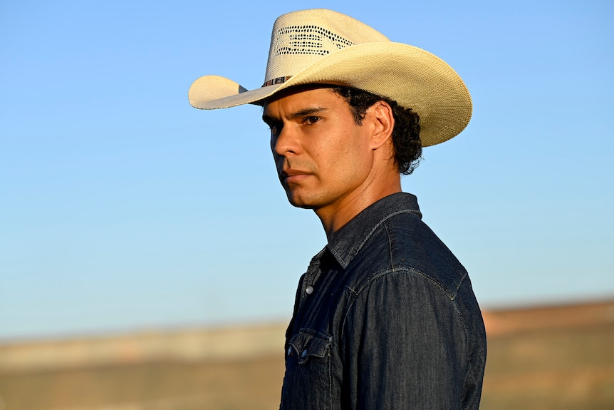 A young man wearing a cowboy-style hat in the Australian outback.