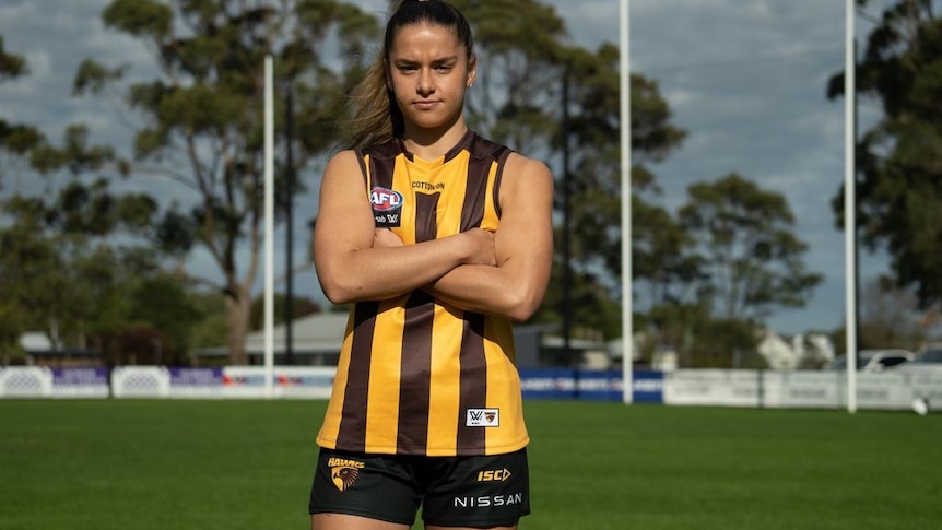 AFLW player Dom Carbone in her Hawks jersey standing on an empty field