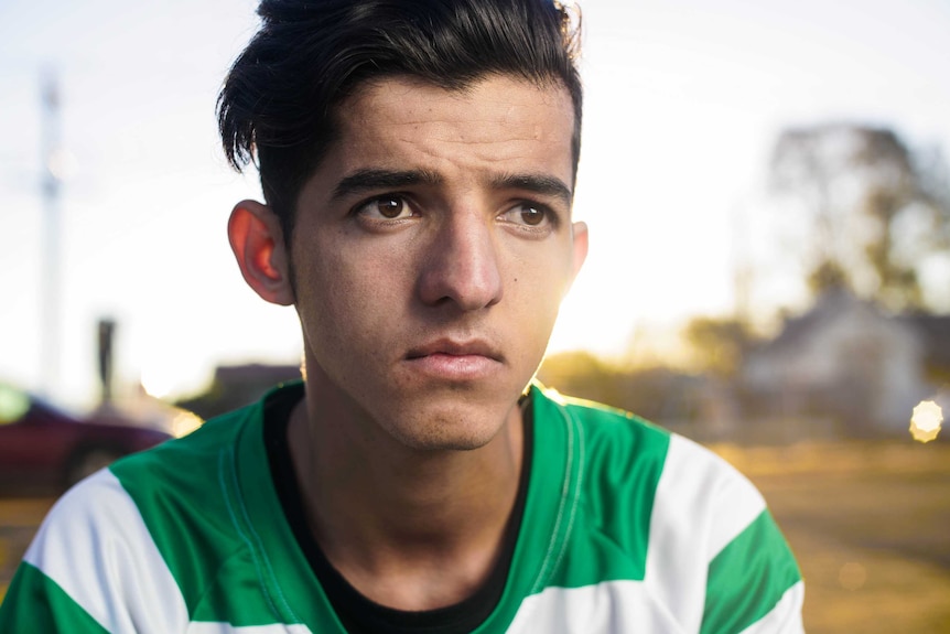 A close-up shot of a young man with dark brown eyes and hair.