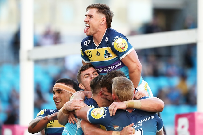 A group of Gold Coast Titans NRL players embrace as they celebrate a try.