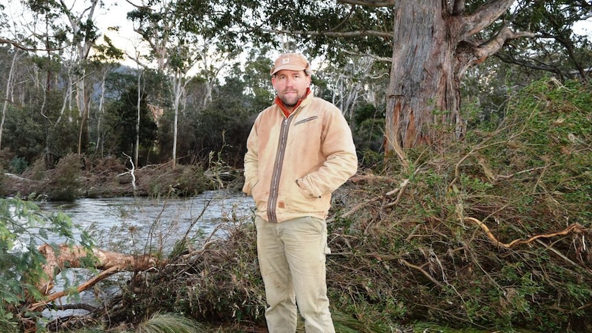 Damian Atkins on the banks of the Mersey River, among the debris left behind by floodwaters.