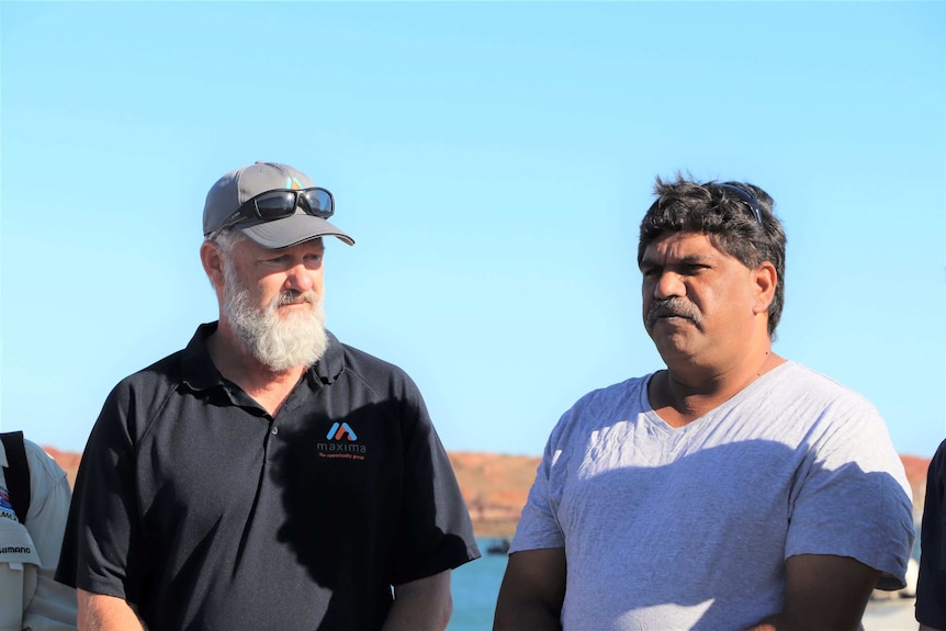 Two men standing next to each other during the day at the Dampier Port.