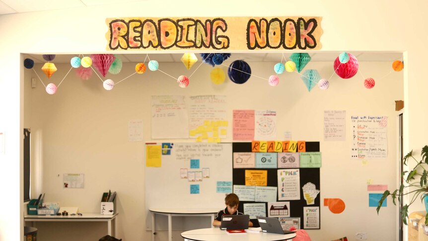 A student sits in a small space quietly reading.