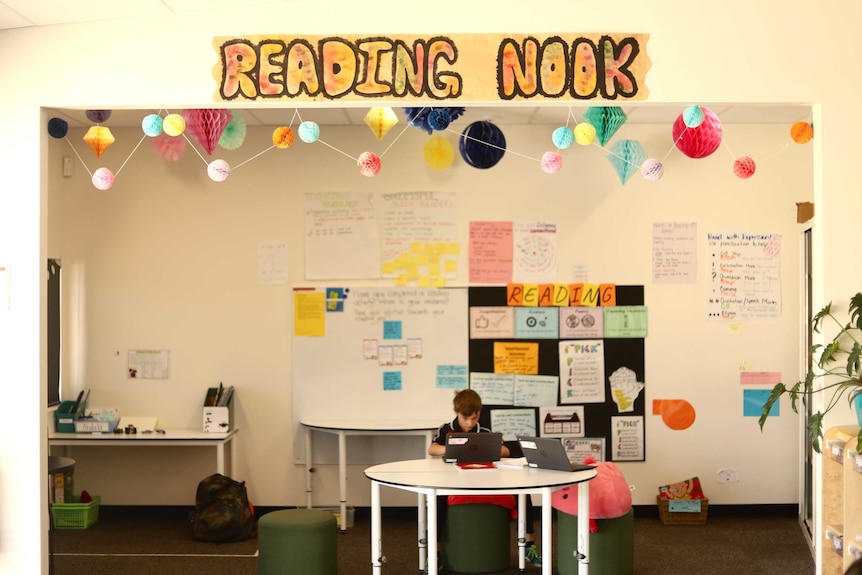 A student sits in a small space quietly reading.