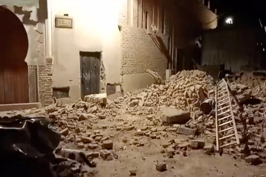 Debris around a stone building with a fallen ladder. 