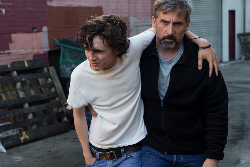 Colour photol of Timothée Chalamet and Steve Carell in alleyway in 2018 film Beautiful Boy.
