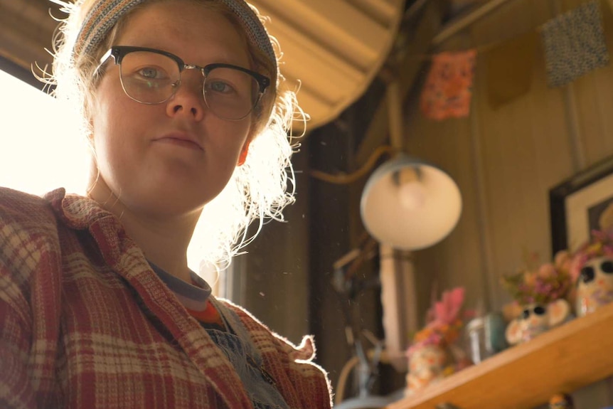 A young woman with a headband works on an art project.