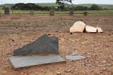 Smashed headstones lying in dirt.