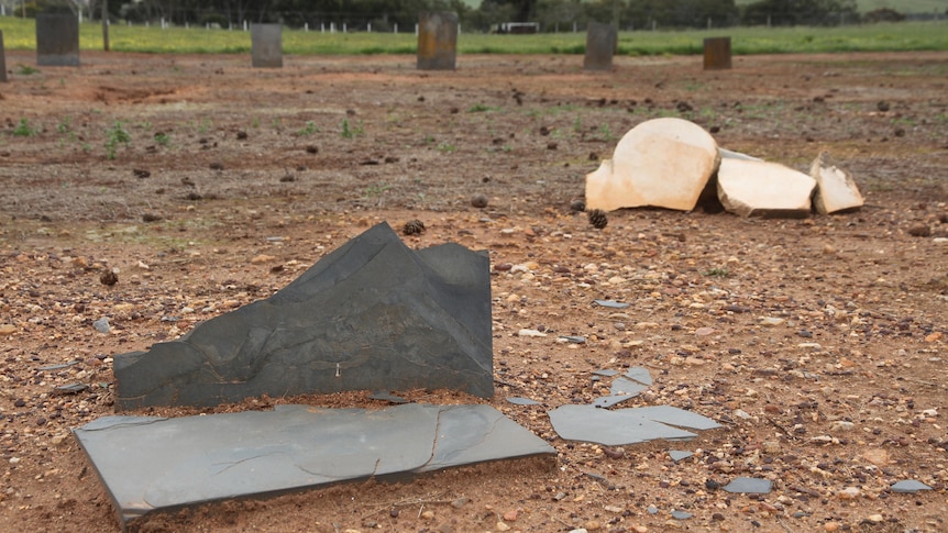 Smashed headstones lying in dirt.