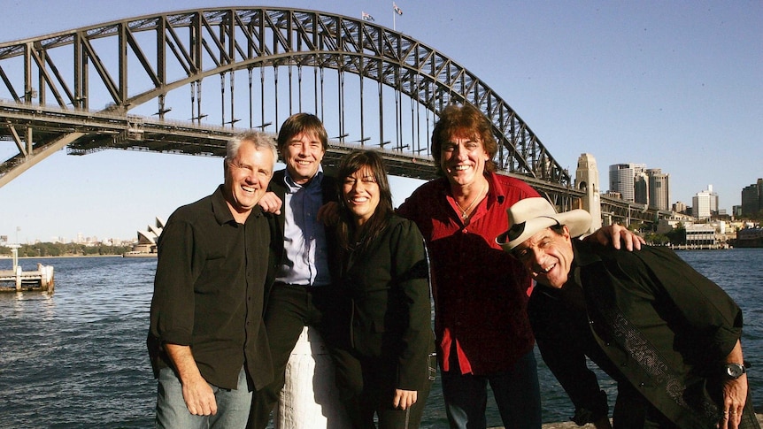 Daryl Braithwaite, John Paul Young, Ally Fowler, Jon English, and Molly Meldrum with the Sydney Harbour Bridge behind.