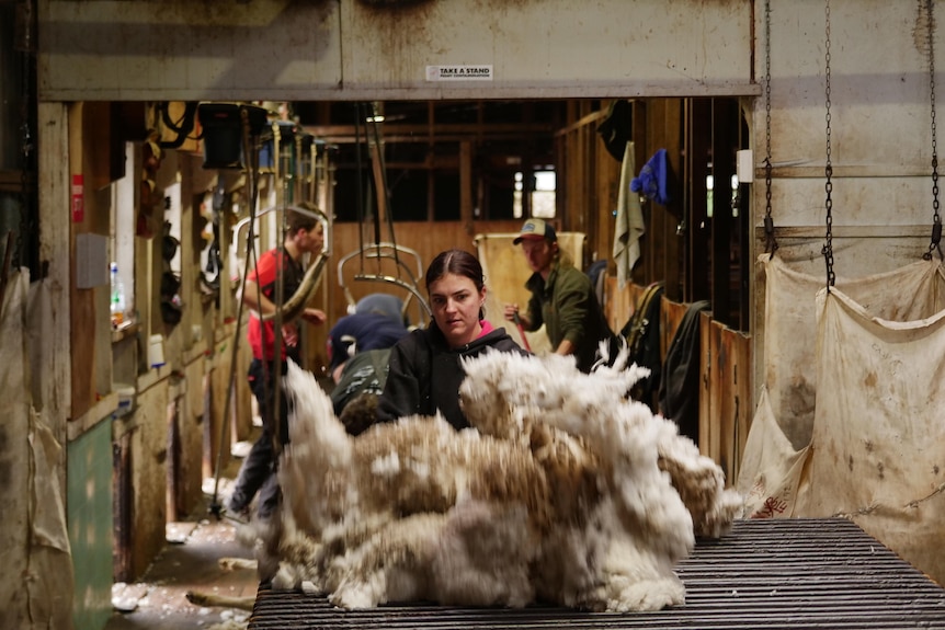 young woman tossing a fleece on the table for classing