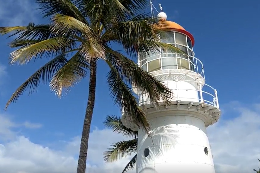 Exterior of a lighthouse with a palm tree.