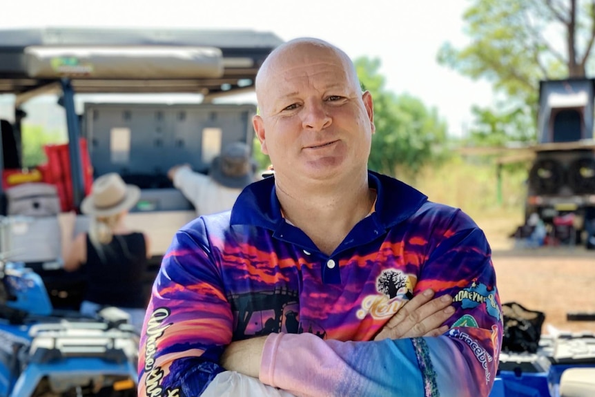 A man, wearing a sunshirt, with his arms crossed.