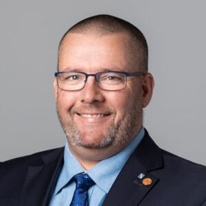 man with stubble and glasses smiling at camera 