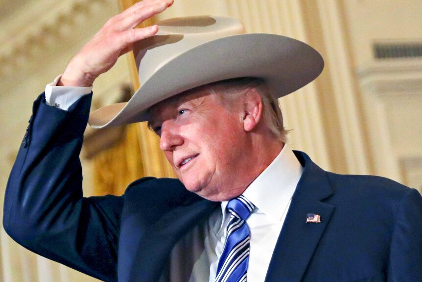 Donald Trump puts a cowboy hat on his head