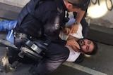 A man on the ground is detained by police.