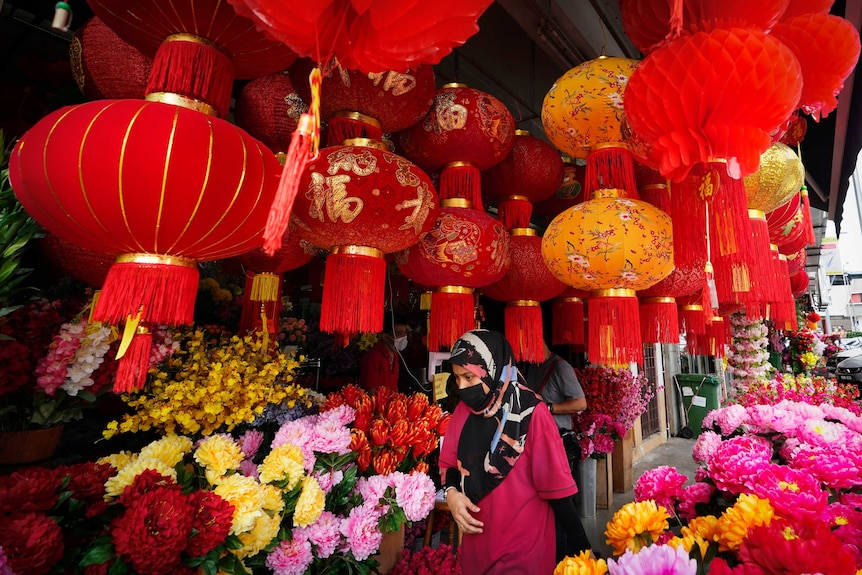 A woman wearing a face mask walks under Chinese New Year lantern decorations