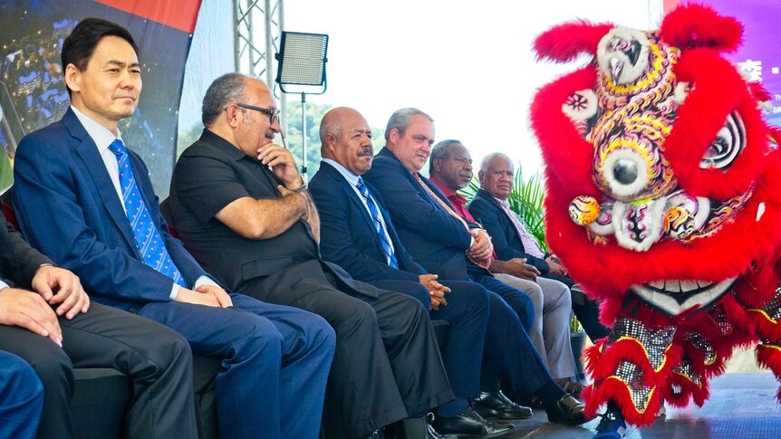 Men on a stage watching a Chinese lion dance