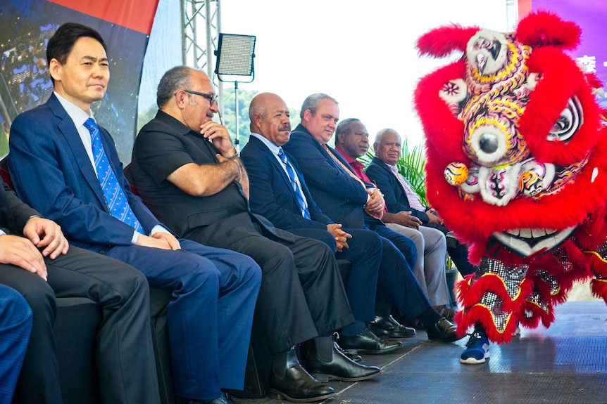 Men on a stage watching a Chinese lion dance