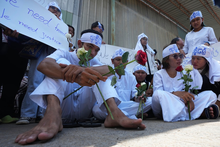 Activists sitting on the ground holding roses. 