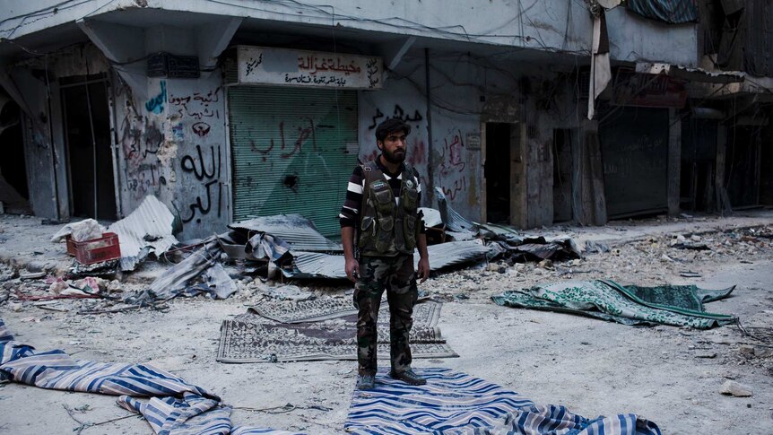 A fighter from the Free Syrian Army stands at a street corner