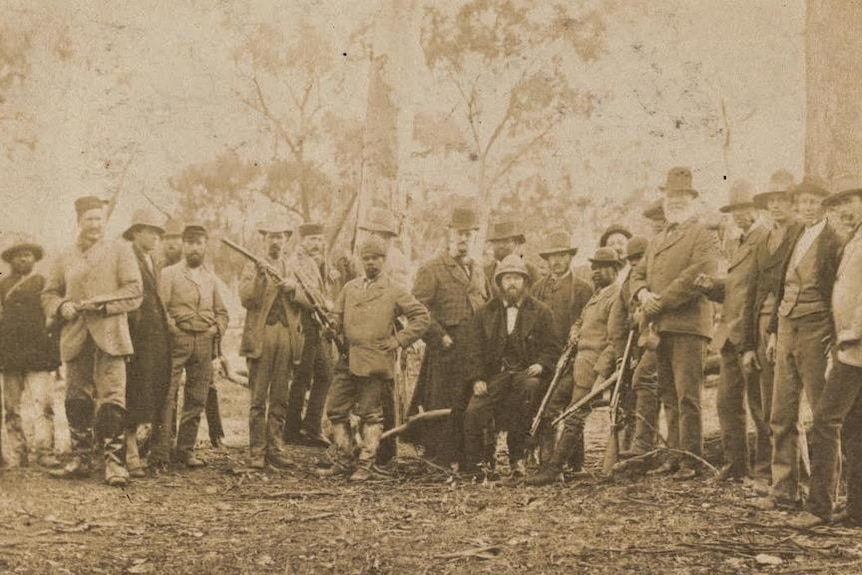 An old sepia image of dozens of men holding guns