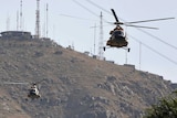 Military helicopters flying with a mountain in the background.