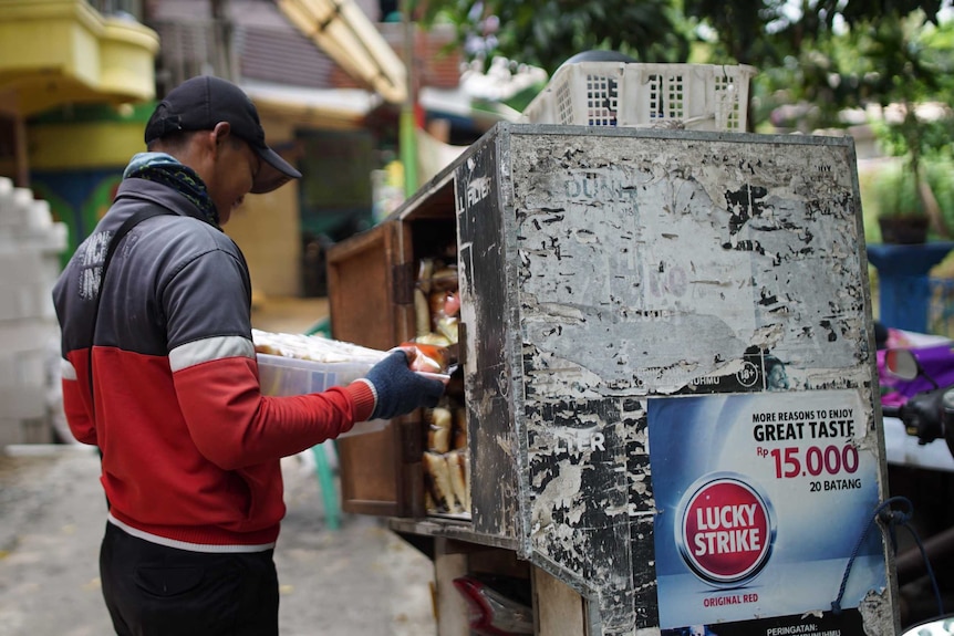 An advertisements for "great taste" cigarettes is plastered onto the side of a street vendor's bread van