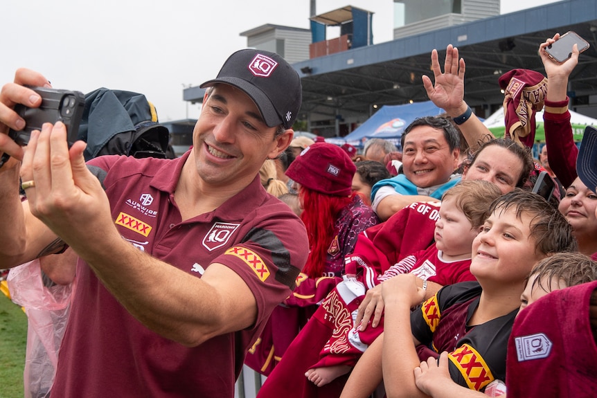 man in maroon shirt takes selfie with fans