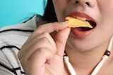 A close-up of a woman eating a potato chip