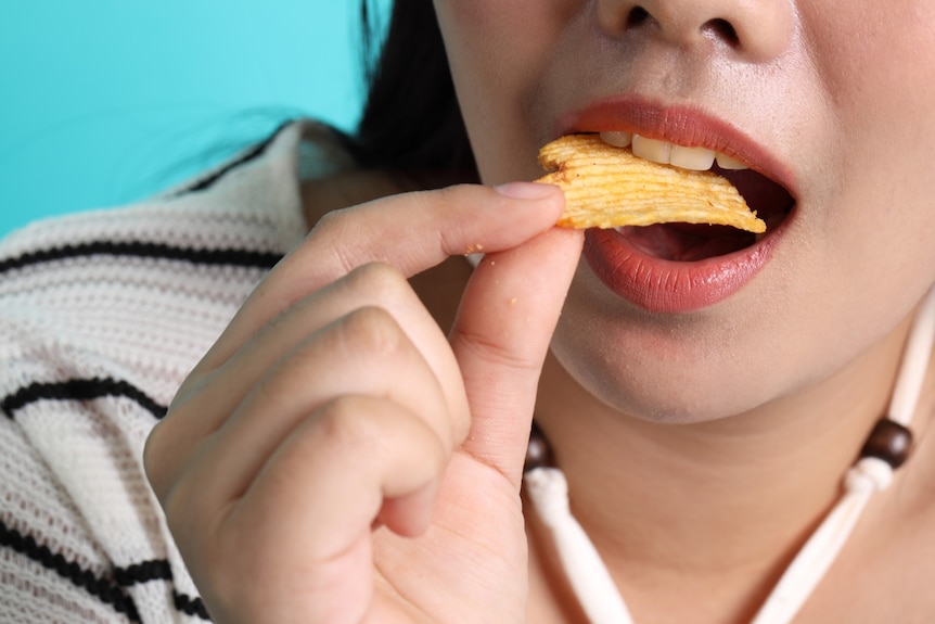 A close-up of a woman eating a potato chip