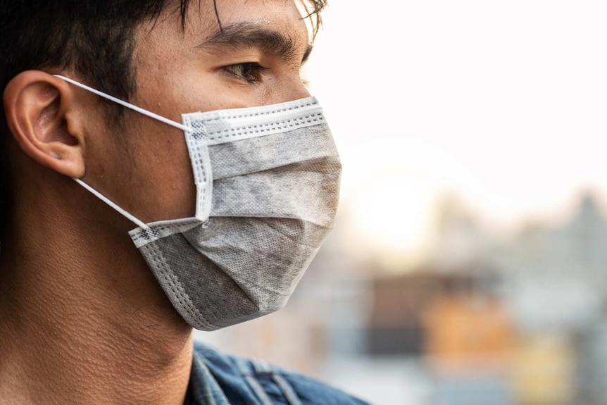 Profile view of a man wearing a surgeon's mask over the lower half of his face