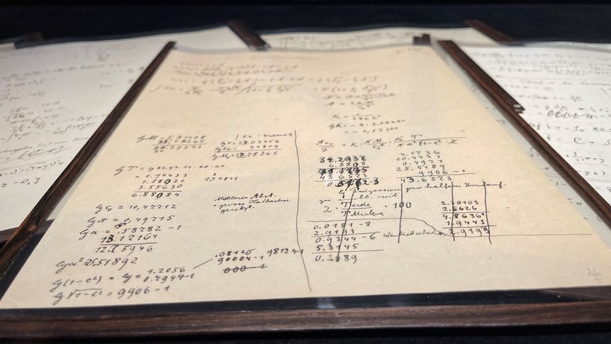 A paper manuscript with writing lays flat on a wooden table 