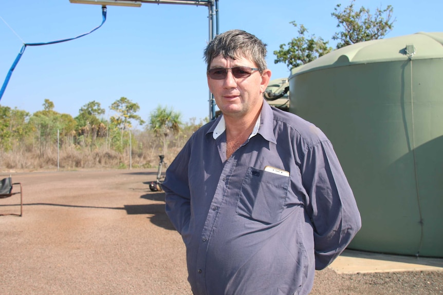Southport Progress Association President Barry Whalan stands next to a water tank