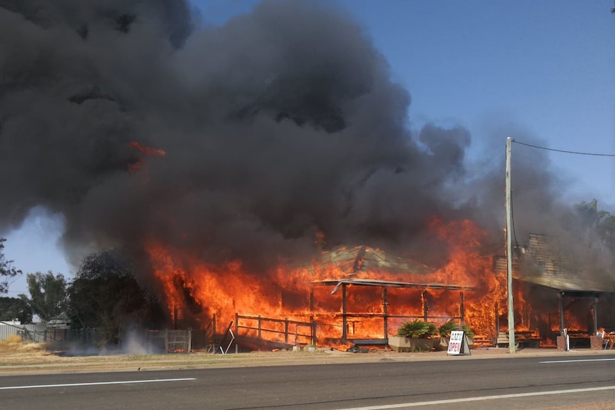 Bright red flames engulf the building and thick dark smoke rises into the sky.