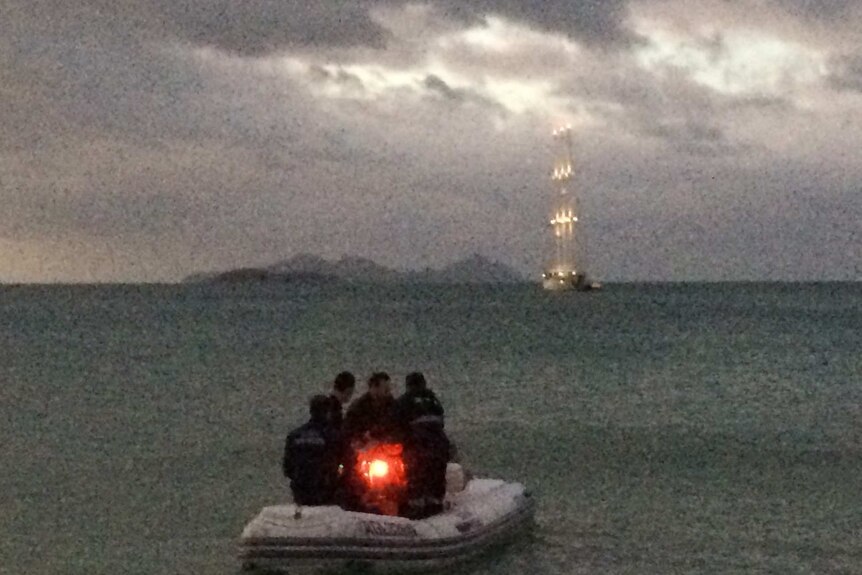 Small boat with people on board heading away from a yacht off shore from Whitehaven Beach