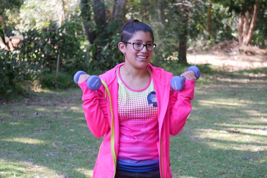 A young woman lifting hand-held weights.