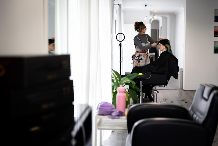 A hairstylist giving a haircut to a person sitting in a salon chair.