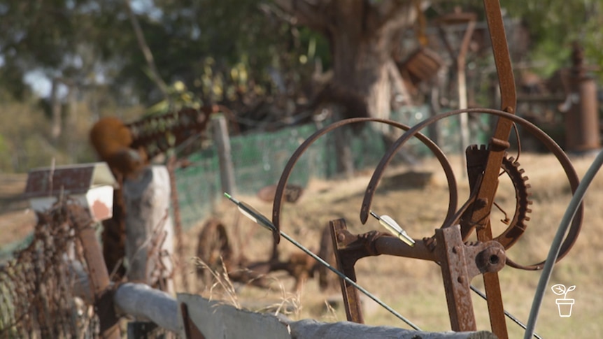 Varying old rusted metal tools leaning against aged country fence