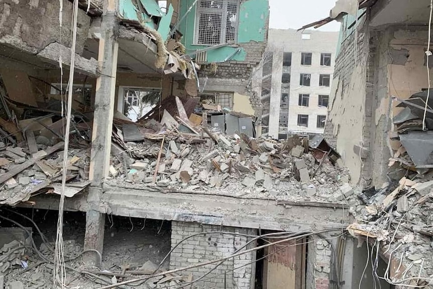 The rubble of a large building, which has been destroyed. Partial walls, twisted metal, concrete and rubble.