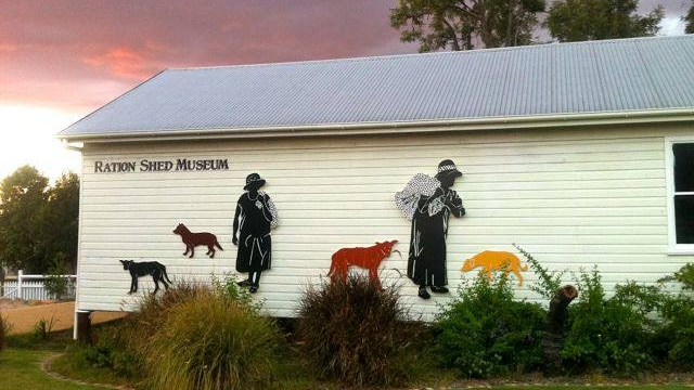 The front wall of the Cherbourg Ration Shed, decorated with stylised cut outs of Indigenous women carrying bags of rations