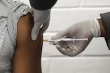 A person receives an injection by a person wearing gloves.
