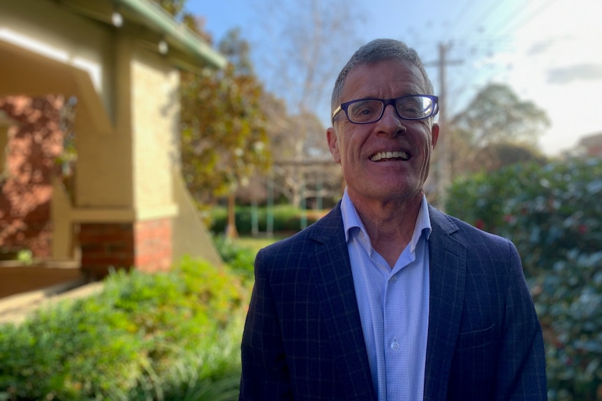 A man in a suit smiles at the camera