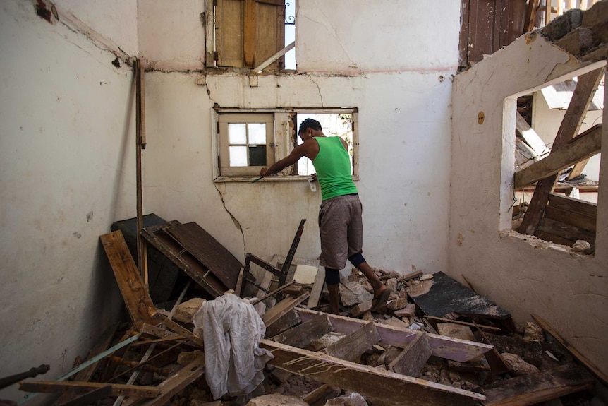 A resident steps on rubble in his collapsed apartment building where two people died during Hurricane Irma.