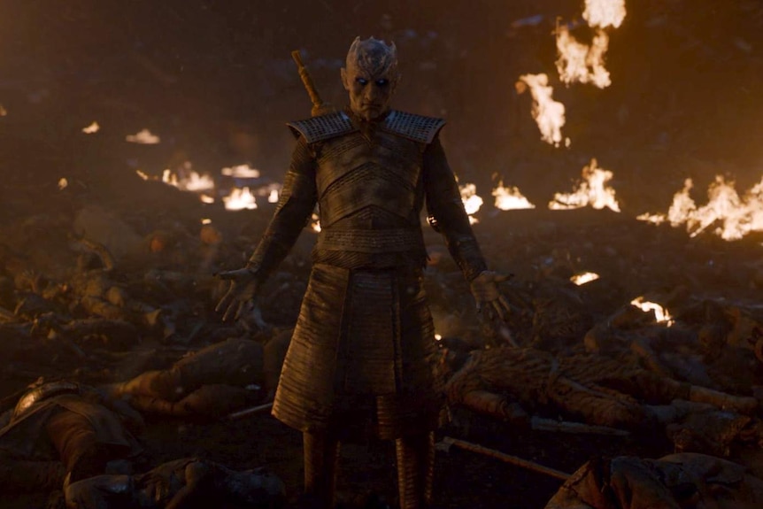 The Night King stands among dead bodies outside the walls of Winterfell and raises his hands slowly to wake the dead.