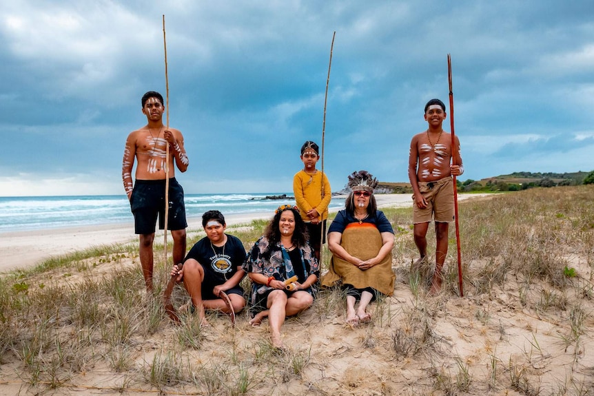 Family portrait of a grandmother, daughter and four grandsons with clay paint and wearing some traditional clothing on a beach