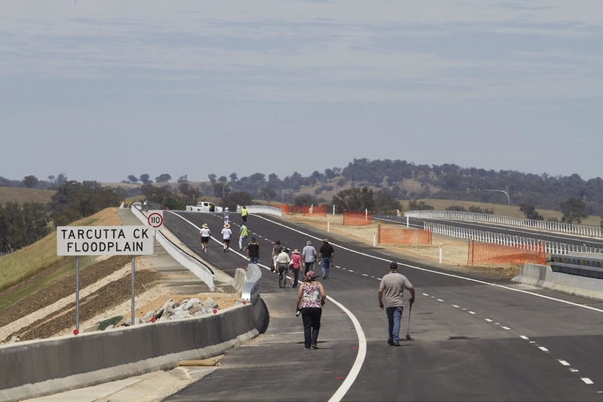 people walk along a large dual-carriageway road