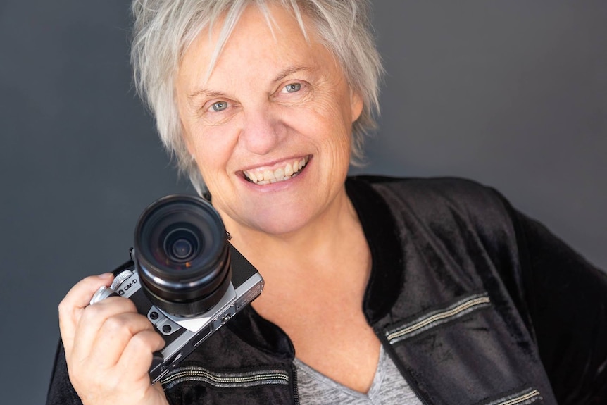 woman holding camera smiles