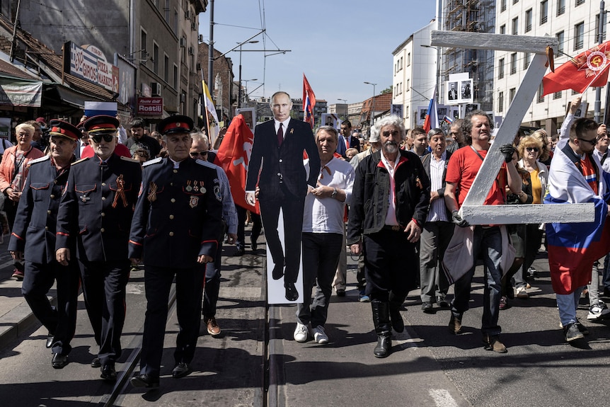 Люди маршируют в Белграде с фигуркой Владимира Путина и табличкой «Z».